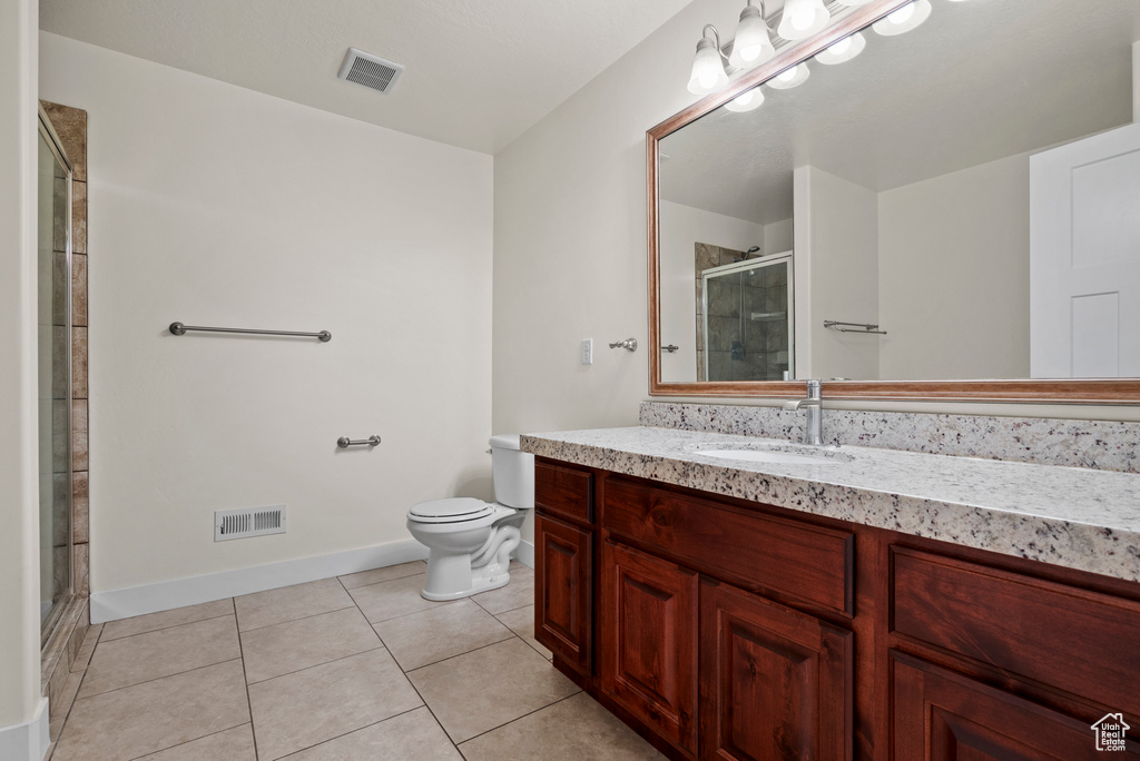 Bathroom featuring toilet, vanity, a shower stall, tile patterned flooring, and baseboards
