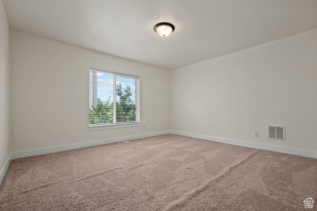 Unfurnished room with baseboards and light carpet