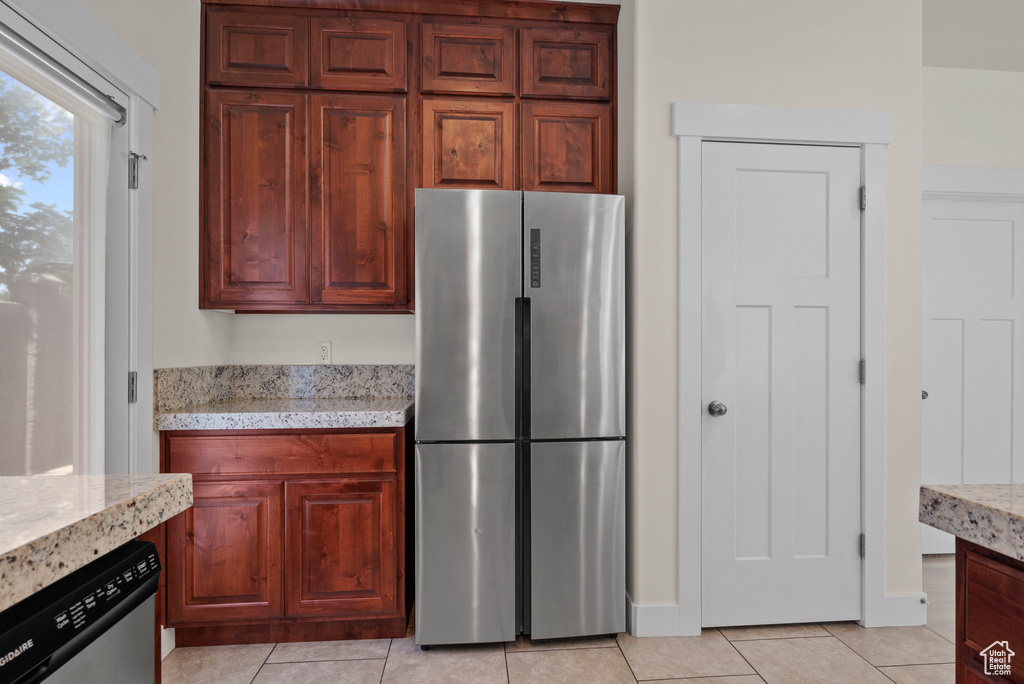 Kitchen featuring stainless steel appliances, light tile patterned flooring, and light stone counters