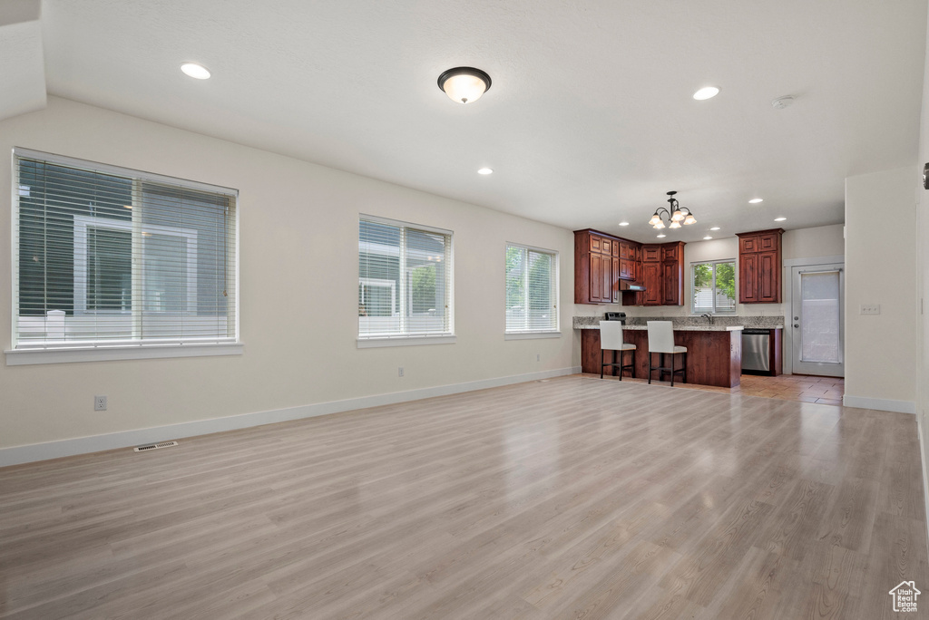 Unfurnished living room featuring a chandelier, recessed lighting, light wood finished floors, and baseboards