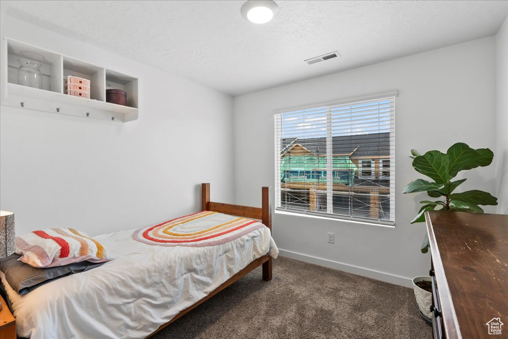 Bedroom with carpet flooring, baseboards, and a textured ceiling