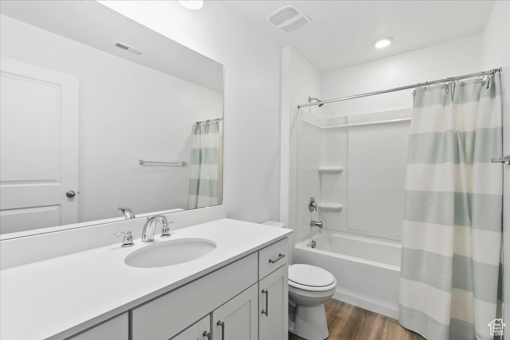 Full bathroom with vanity, wood finished floors, toilet, and shower / tub combo
