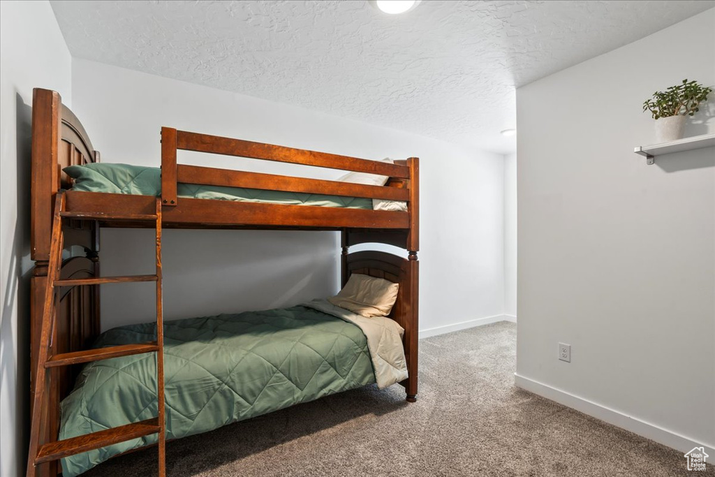 Bedroom featuring carpet floors, a textured ceiling, and baseboards