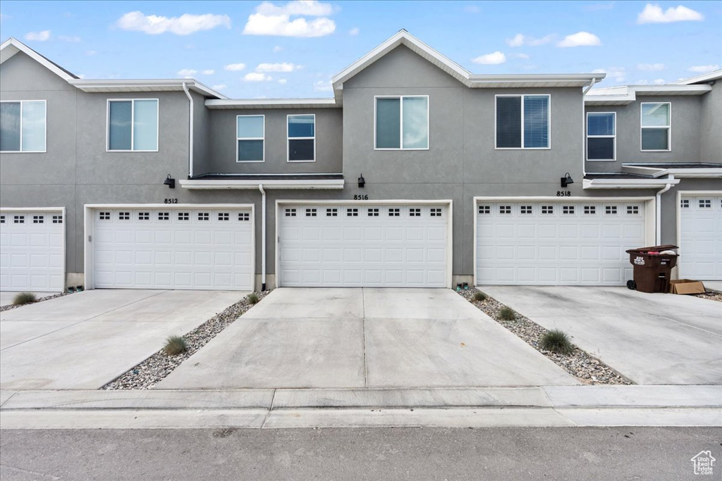 Multi unit property with stucco siding, a garage, and driveway