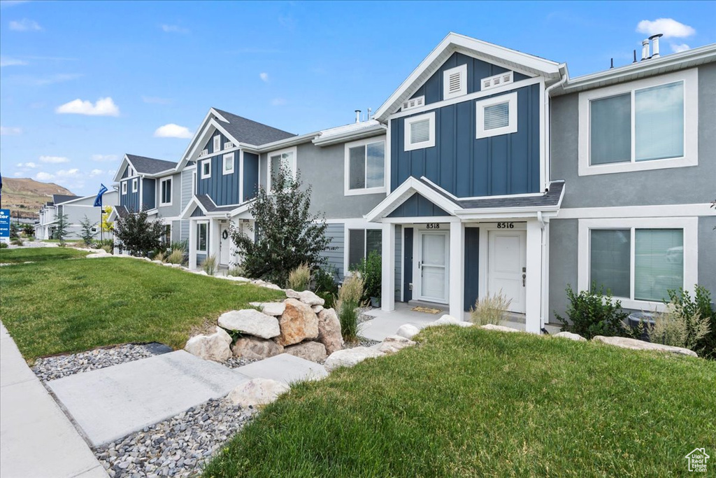 Townhome / multi-family property with board and batten siding, a front lawn, and a residential view