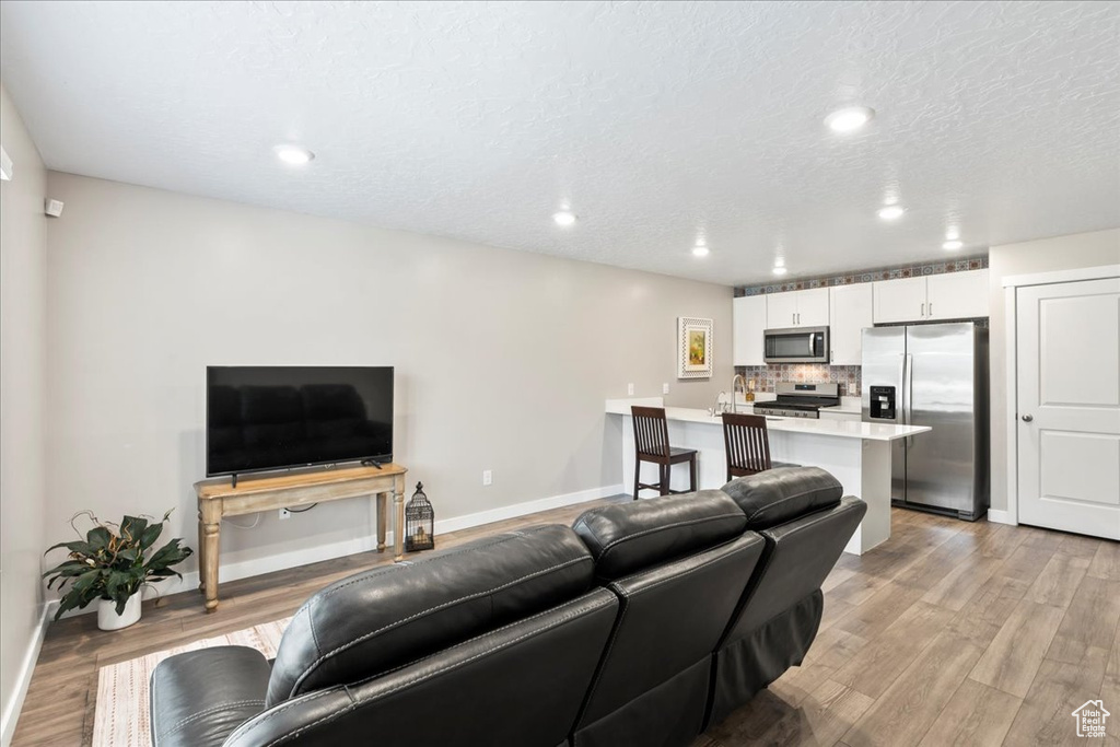 Living room featuring baseboards, light wood-style floors, recessed lighting, and a textured ceiling