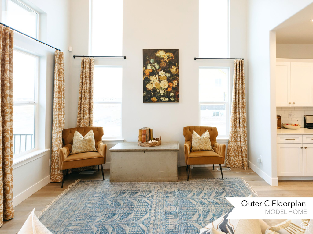 Sitting room featuring light wood-style floors, a high ceiling, and baseboards
