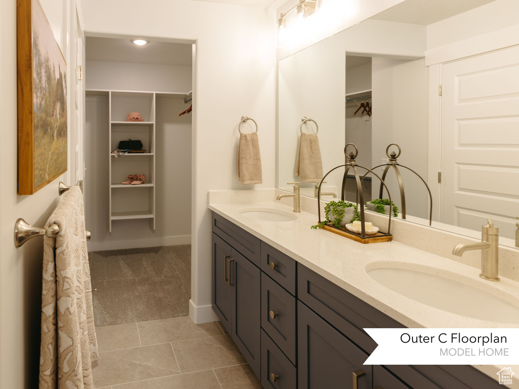 Full bath with double vanity, a spacious closet, tile patterned flooring, and baseboards