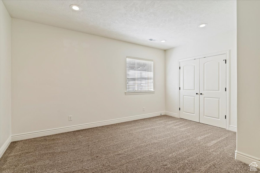 Unfurnished bedroom featuring carpet, recessed lighting, baseboards, a textured ceiling, and a closet