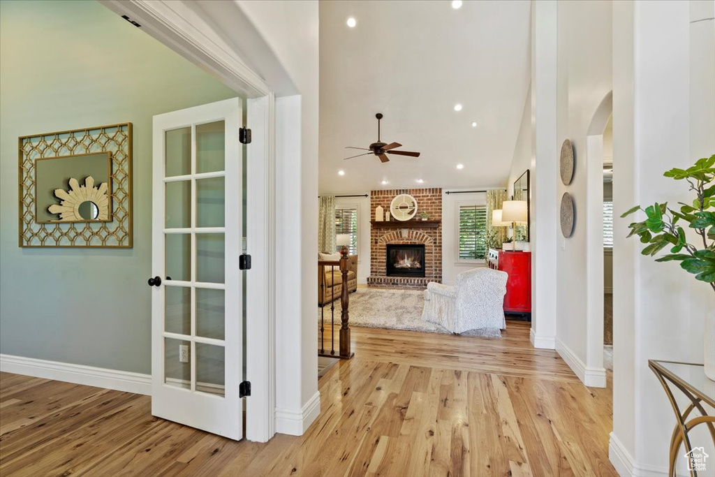 Hallway with light wood-style floors, arched walkways, baseboards, recessed lighting, and lofted ceiling