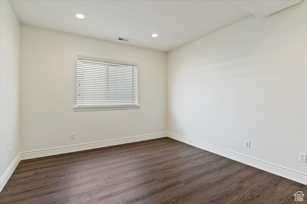 Spare room featuring dark wood-style flooring, recessed lighting, and baseboards