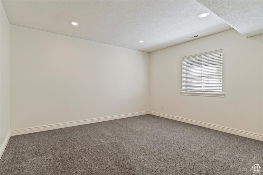 Carpeted spare room with recessed lighting, baseboards, and a textured ceiling