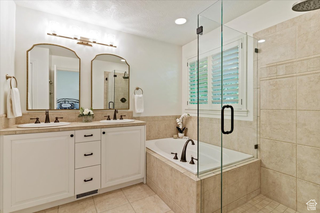 Full bathroom with a shower stall, a bath, tile patterned floors, double vanity, and a textured ceiling