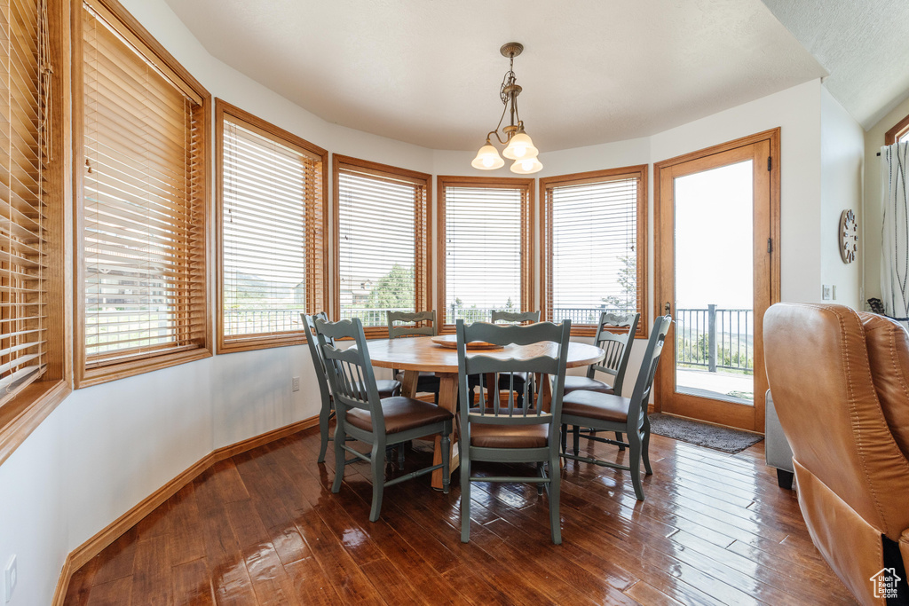 Dining area with dark wood-style flooring, a chandelier, and baseboards