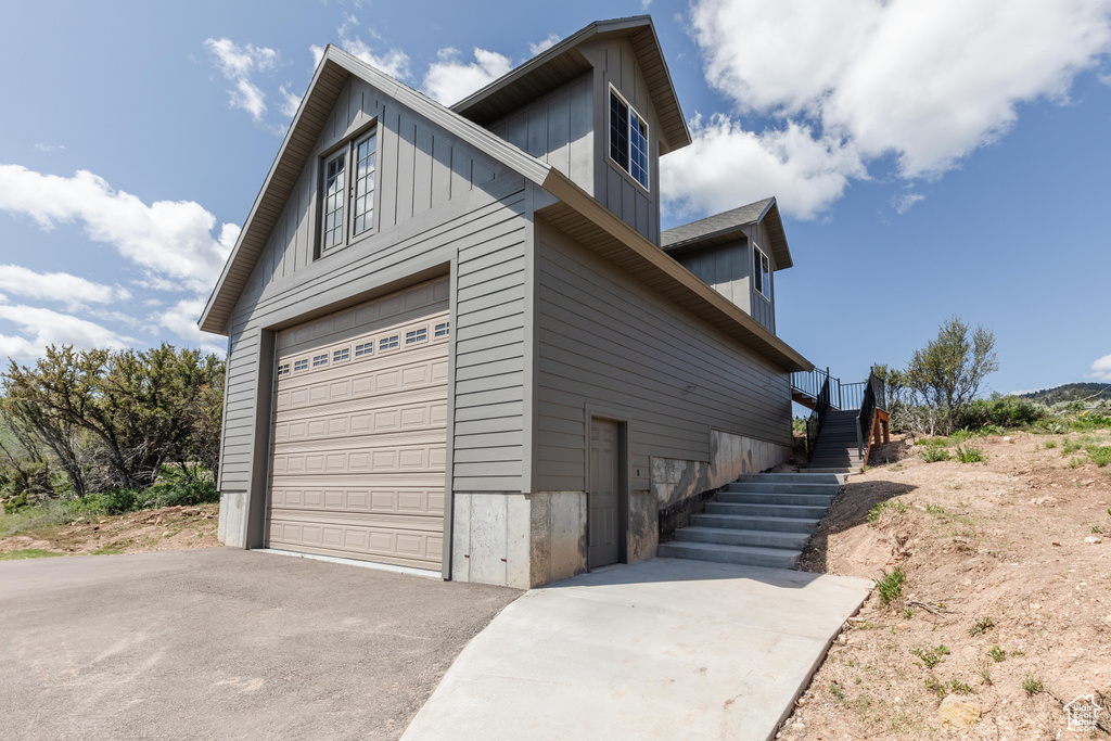 View of home\\\'s exterior featuring asphalt driveway, board and batten siding, and stairs