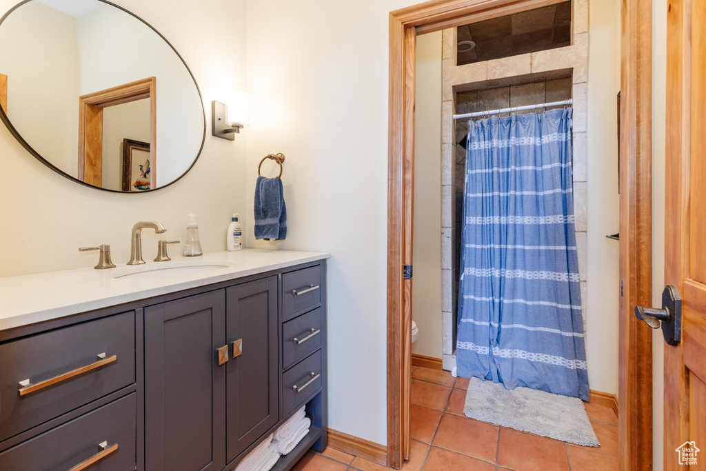 Bathroom with tile patterned floors, vanity, toilet, curtained shower, and baseboards