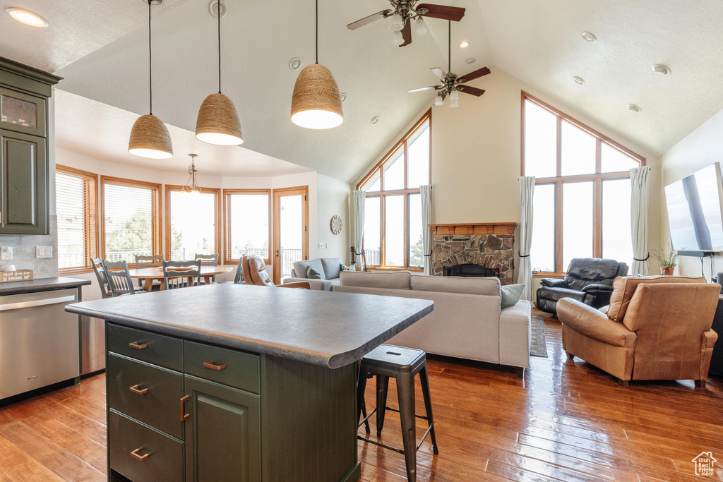 Kitchen with dishwasher, high vaulted ceiling, a kitchen island, a breakfast bar, and a ceiling fan