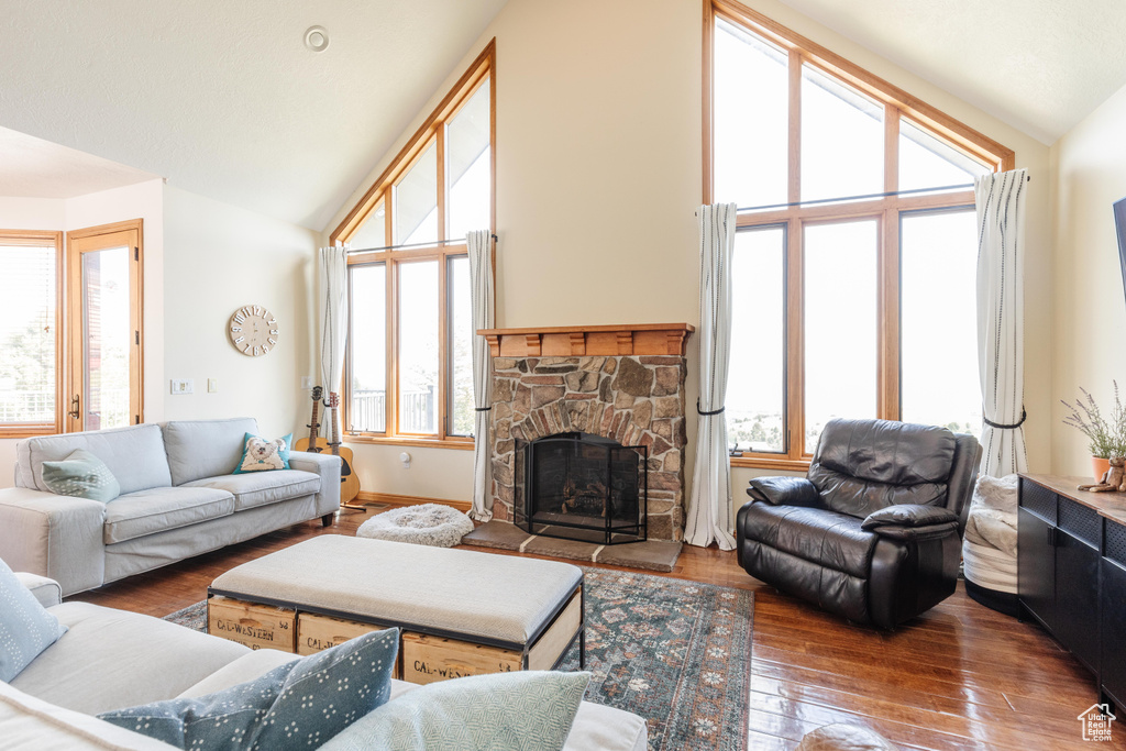 Living room with vaulted ceiling, a fireplace, and hardwood / wood-style floors