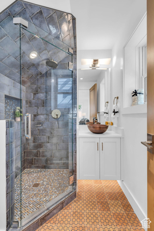 Full bathroom featuring vanity, a shower stall, and baseboards