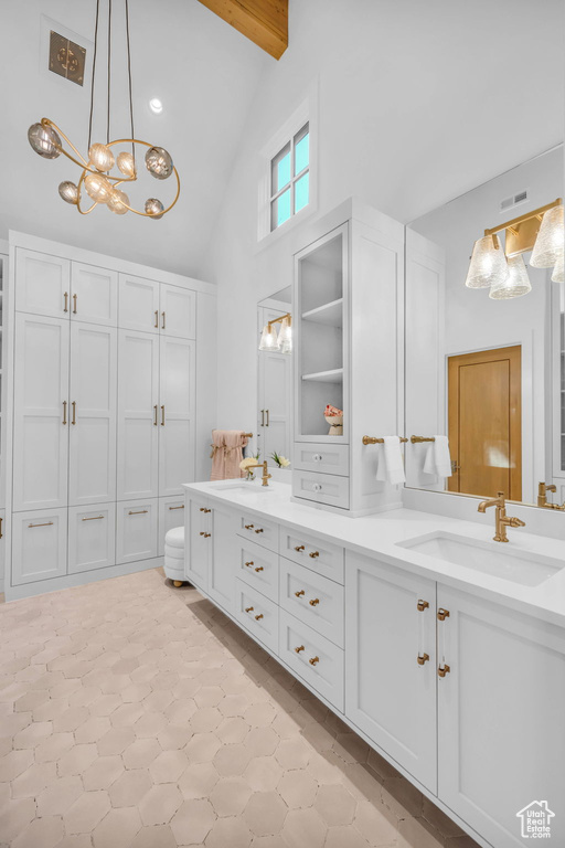 Bathroom featuring a chandelier, double vanity, high vaulted ceiling, a closet, and beam ceiling