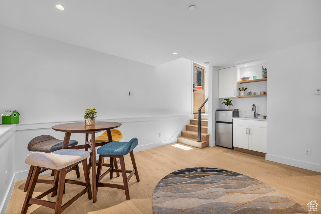 Dining room with bar with sink, light wood-style floors, stairway, recessed lighting, and baseboards