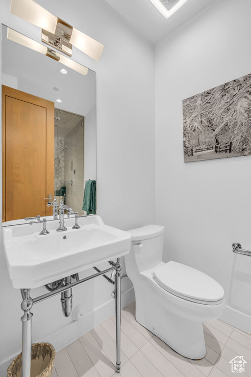 Full bathroom with toilet, a shower, baseboards, and a sink
