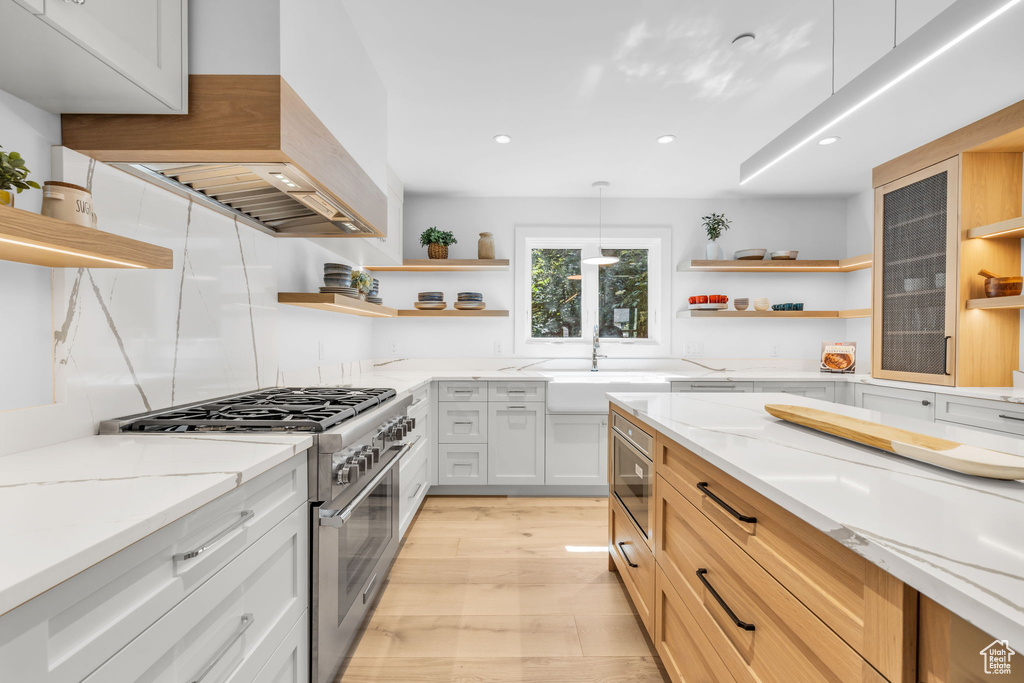Kitchen featuring open shelves, high end stove, custom range hood, a sink, and recessed lighting