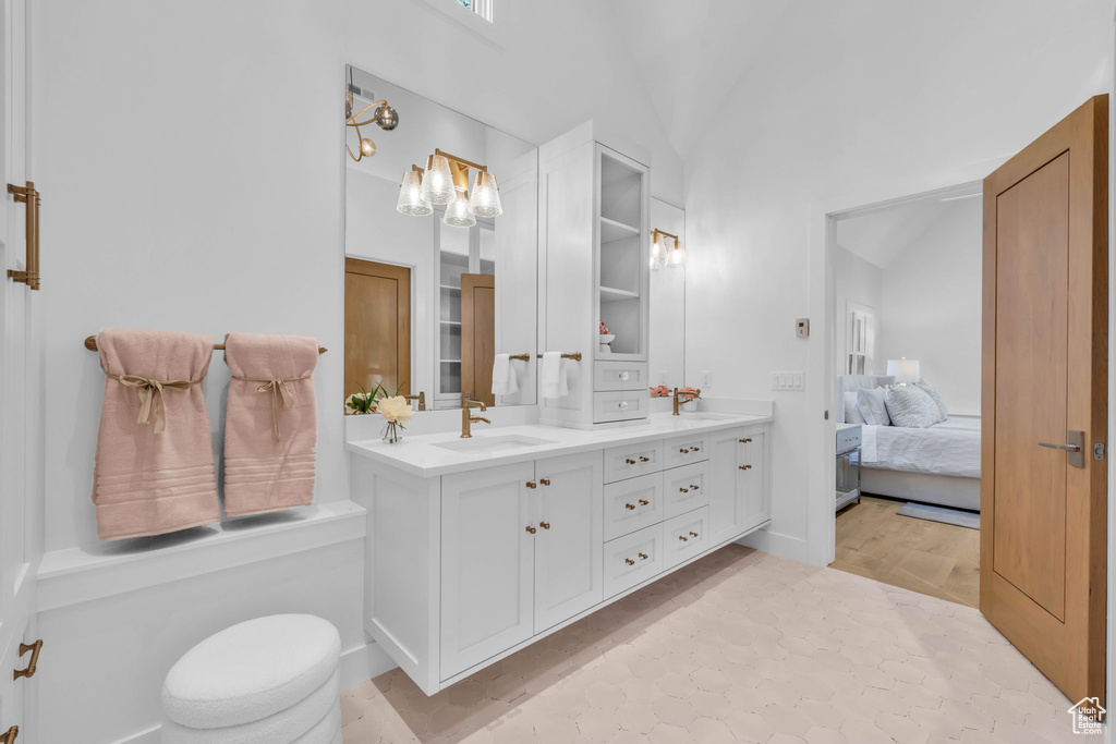 Full bath featuring vanity, ensuite bath, a chandelier, and lofted ceiling