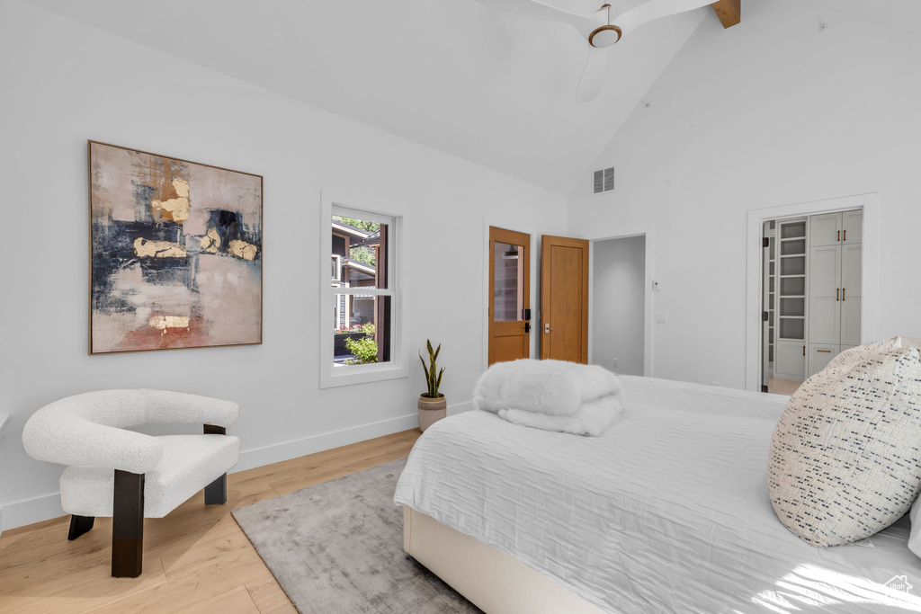 Bedroom featuring wood finished floors, baseboards, high vaulted ceiling, and a ceiling fan