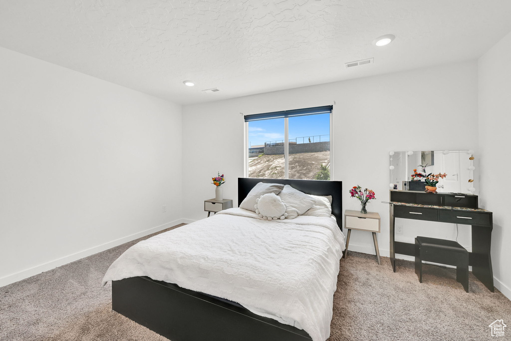 Carpeted bedroom featuring baseboards and a textured ceiling