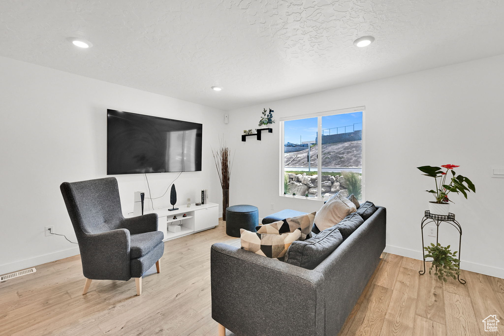 Living room with light wood finished floors, baseboards, and recessed lighting