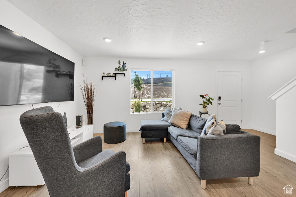 Living area with a textured ceiling, light wood-style flooring, recessed lighting, and baseboards
