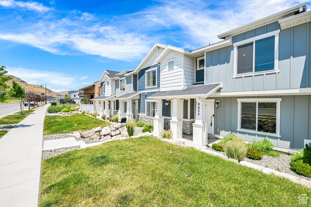 View of property featuring board and batten siding, a residential view, and a front yard