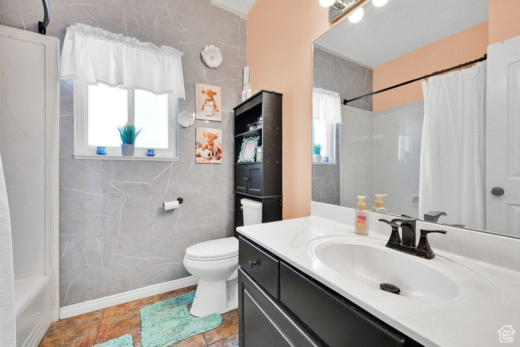 Full bathroom featuring vanity, toilet, and shower / bathtub combination with curtain