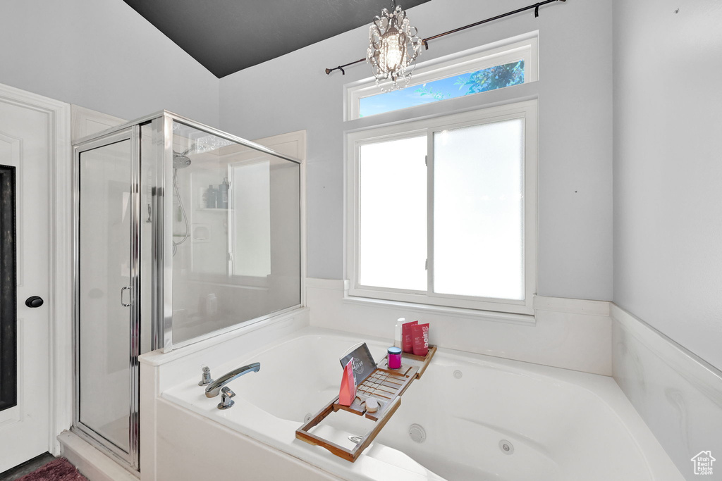 Bathroom featuring a stall shower, a whirlpool tub, and a chandelier