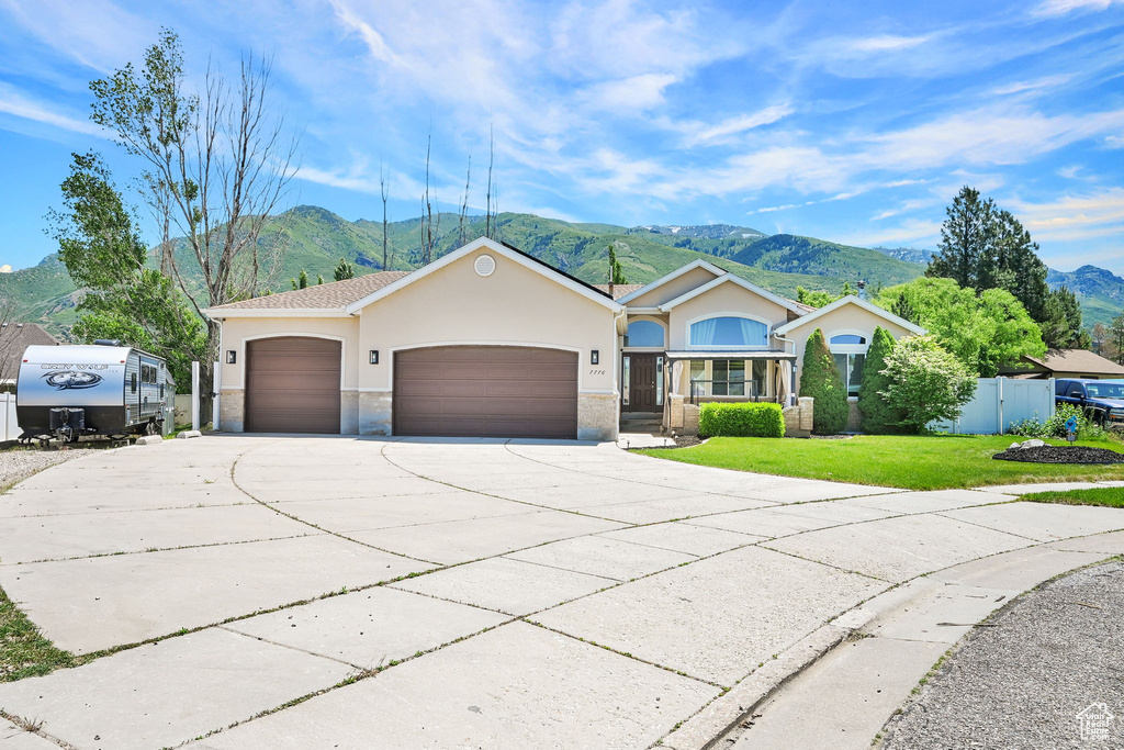 Ranch-style house with a mountain view, driveway, stucco siding, and an attached garage