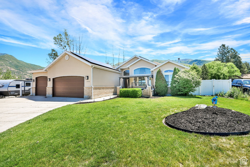 Single story home featuring stucco siding, solar panels, a mountain view, an attached garage, and concrete driveway