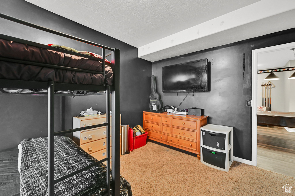 Bedroom featuring baseboards, a textured ceiling, and carpet