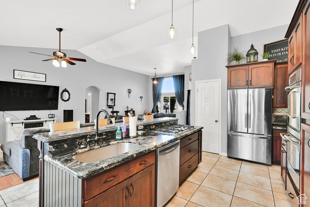 Kitchen featuring stainless steel appliances, a sink, open floor plan, ceiling fan, and vaulted ceiling