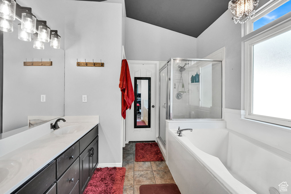 Full bath with a stall shower, double vanity, a bath, a chandelier, and baseboards
