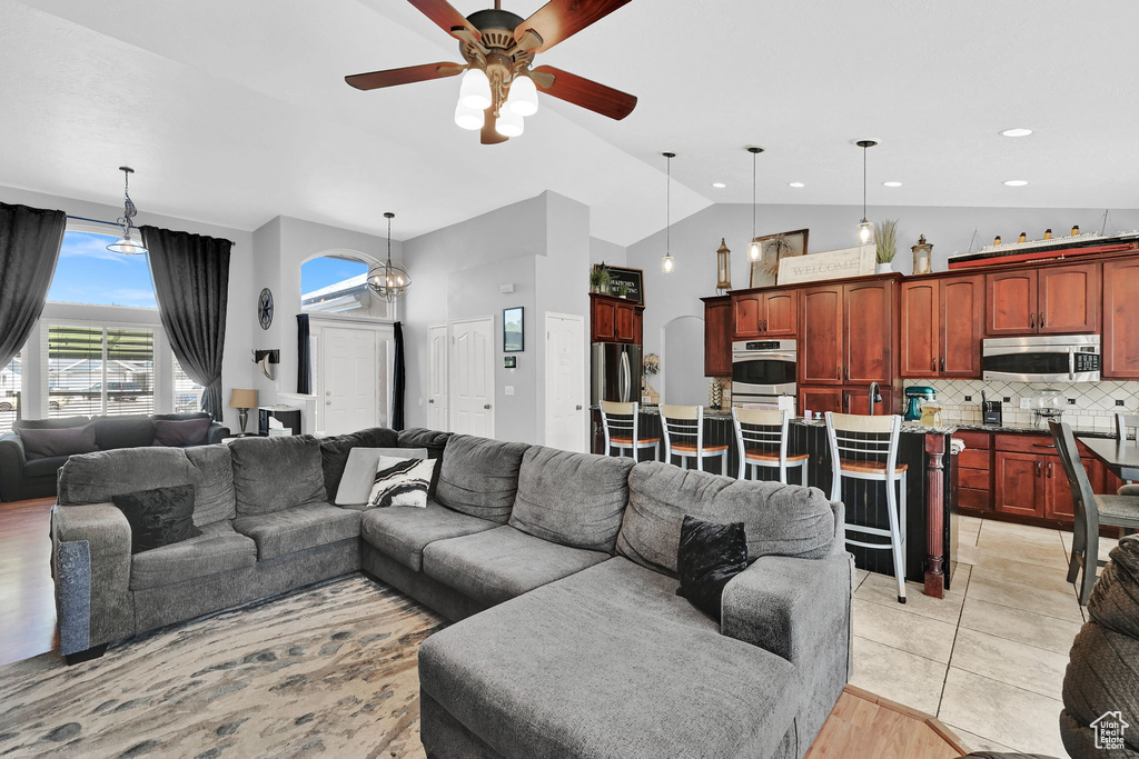 Living area with a ceiling fan, high vaulted ceiling, and recessed lighting