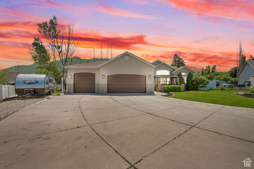 View of front facade with an attached garage, concrete driveway, stucco siding, and stone siding