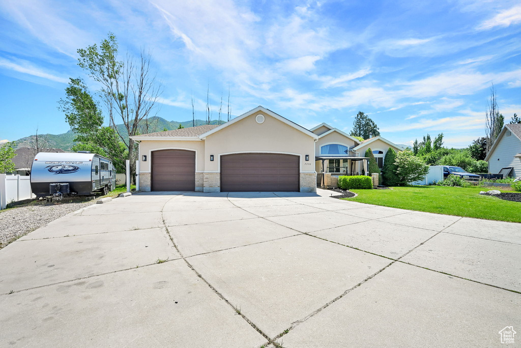 Ranch-style home with an attached garage, concrete driveway, stucco siding, and stone siding