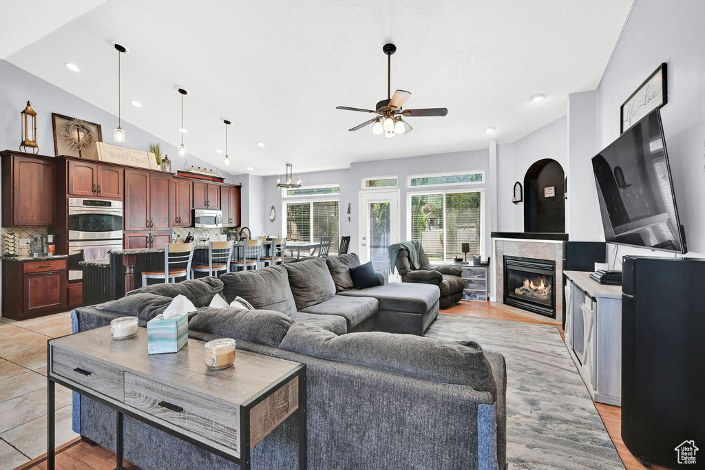 Living room featuring a ceiling fan, a fireplace, recessed lighting, light wood-style flooring, and vaulted ceiling