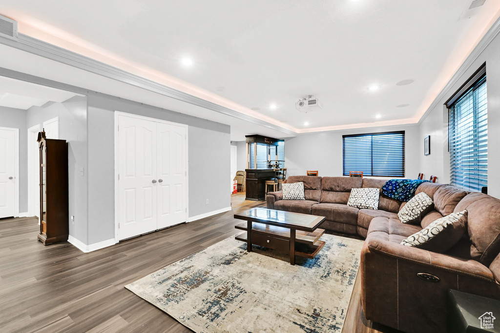 Living area featuring wood finished floors, baseboards, a raised ceiling, and recessed lighting