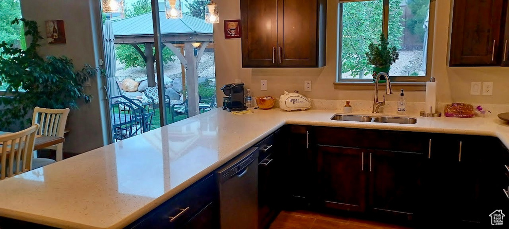 Kitchen with dishwasher, a sink, a peninsula, and dark tile patterned flooring