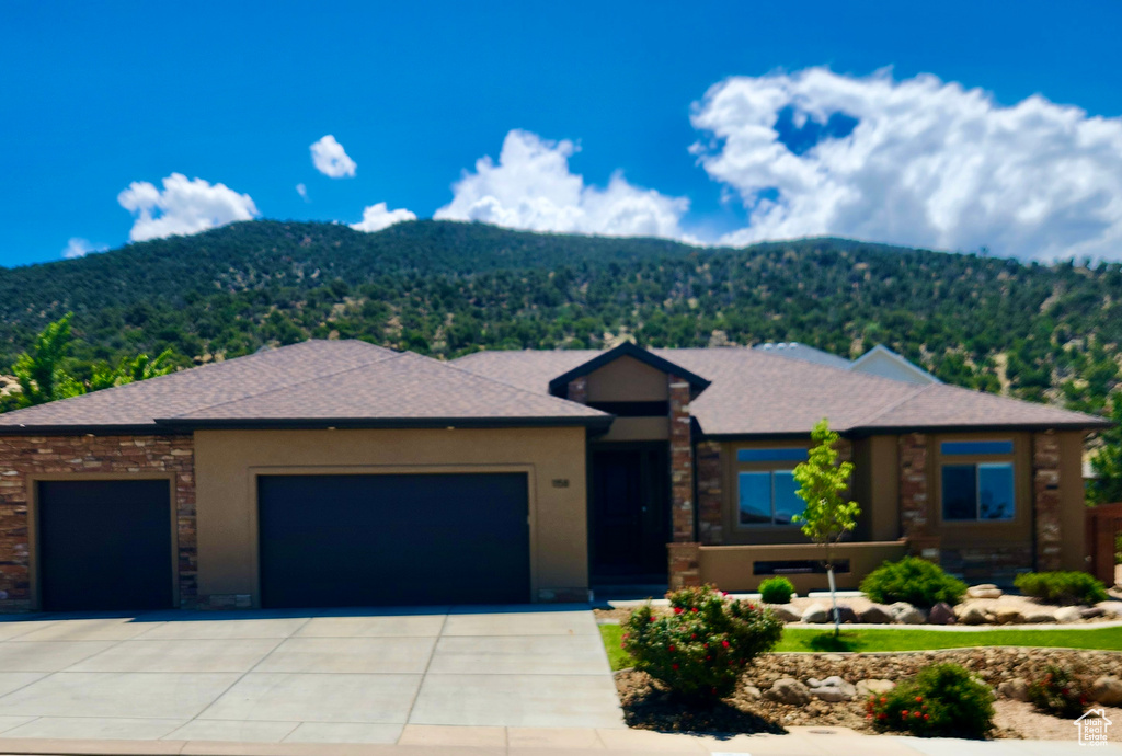 Prairie-style house with an attached garage, a mountain view, and driveway