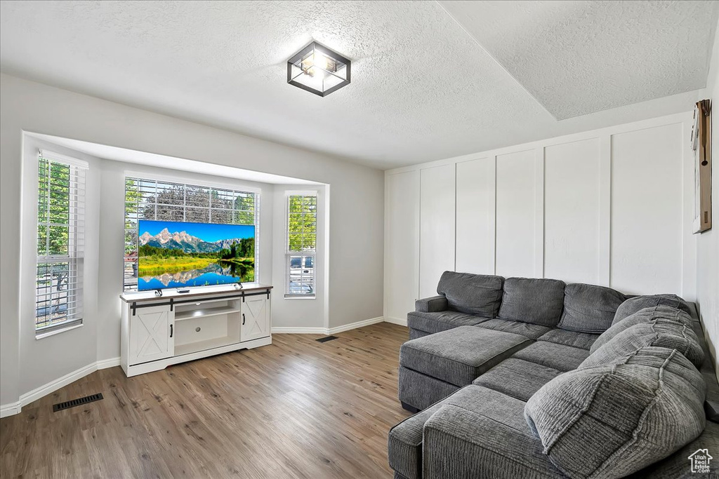 Living room with a textured ceiling, wood finished floors, and baseboards