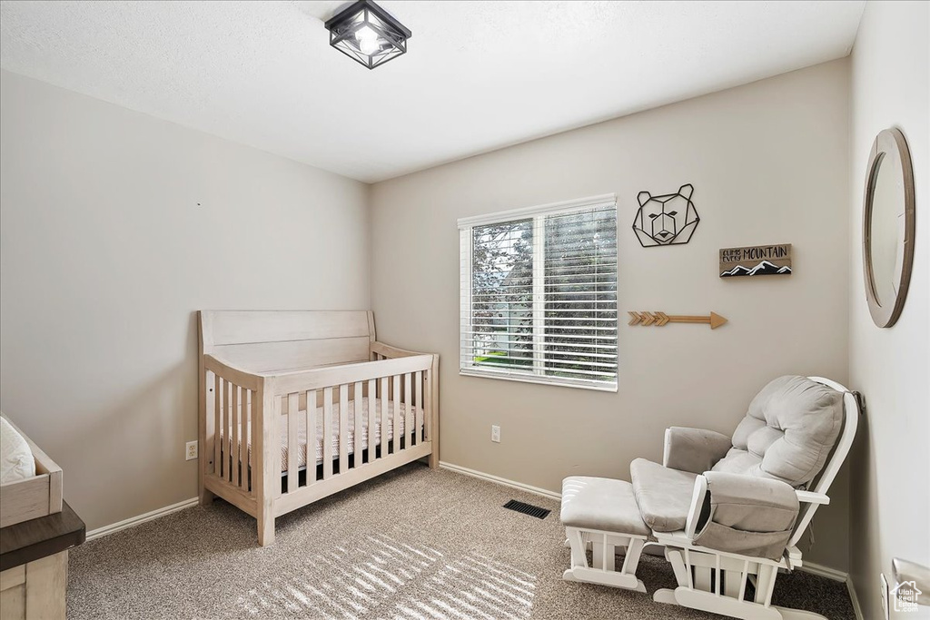 Carpeted bedroom with a nursery area and baseboards