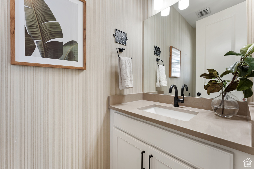 Bathroom with wallpapered walls and vanity